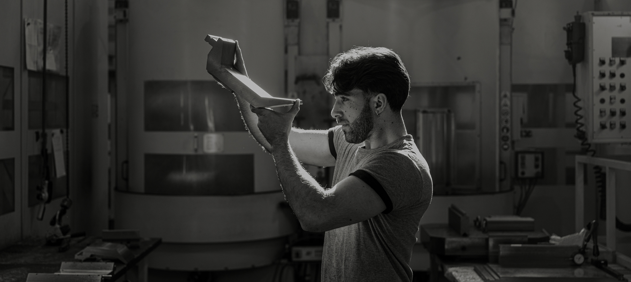 IMTE engineer inspecting a precision metal component under workshop light, symbolizing innovation, quality control and advanced manufacturing."